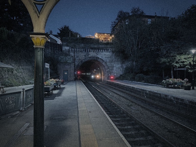 Knaresborough station platform at night, a train emerging from the tunnel